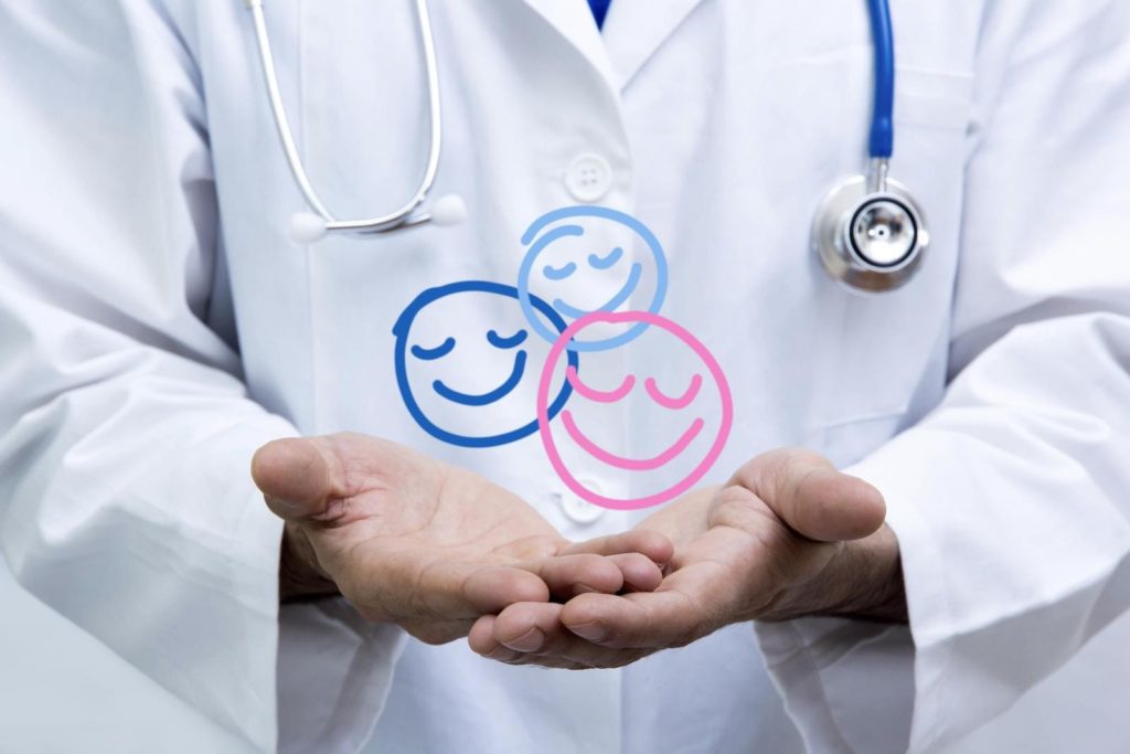 A pediatrician with their arms extended with three smiling faces drawn