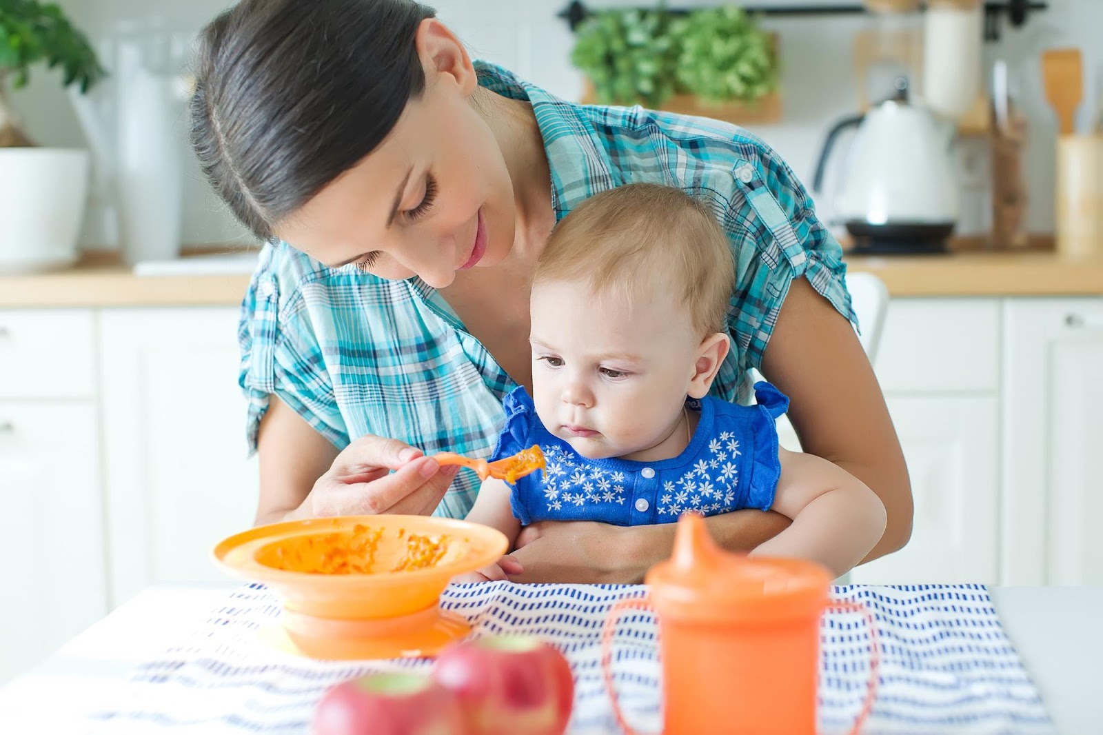 A young mother feeding her baby puree